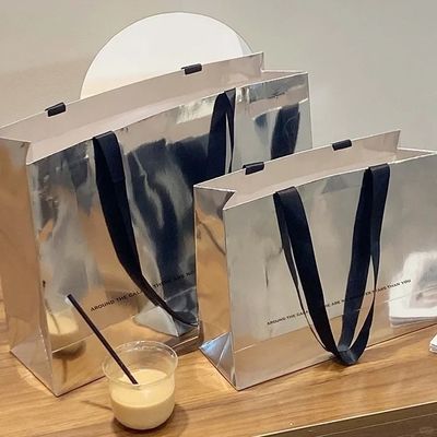 Buen precio Bolsa de regalo de papel para ropa, bolsa de compras, tarjeta plateada, bolsa de mano de papel kraft con impresión de logotipo en línea